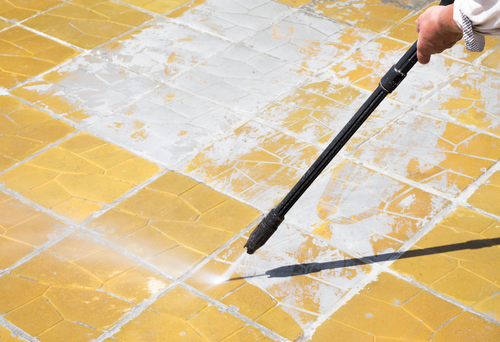 Worker is cleaning anexternal floor with a high pressure water.